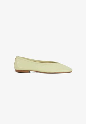 Chaussure de ballet plate brillante de couleur jaune pâle avec bout pointu et petit talon marron, vue de côté sur fond blanc.