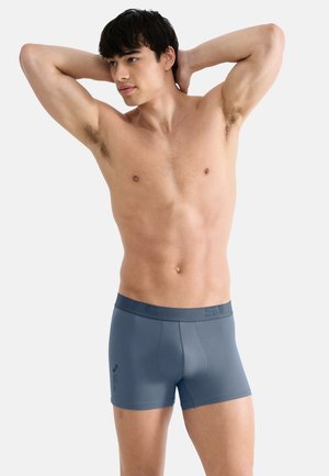 Blue stretch fabric boxer briefs with a seamless design, featuring a thick waistband with embossed logo and a smooth texture.