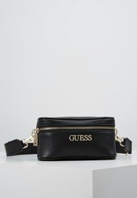 Černá kožená crossbody taška se zlatým kováním, zipovým uzavíráním a reliéfním logem na přední straně. Obsahuje nastavitelné rameno.