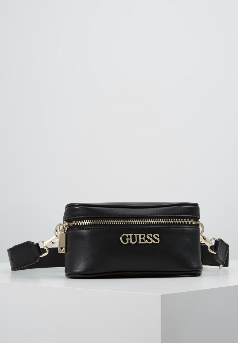 Černá kožená crossbody taška se zlatým kováním, zipovým uzavíráním a reliéfním logem na přední straně. Obsahuje nastavitelné rameno.