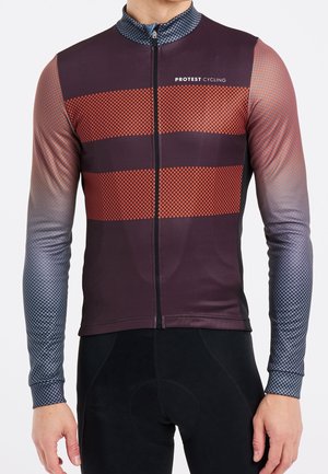Man draagt een lange-mouwen fietsjersey met rood-zwart geblokte strepen en de tekst "PROTEST CYCLING" op de borst.