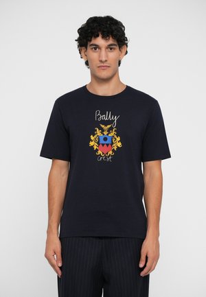 Navy blue crew neck t-shirt made of cotton; features a colorful heraldic crest design with "Bally" text and intricate gold accents.