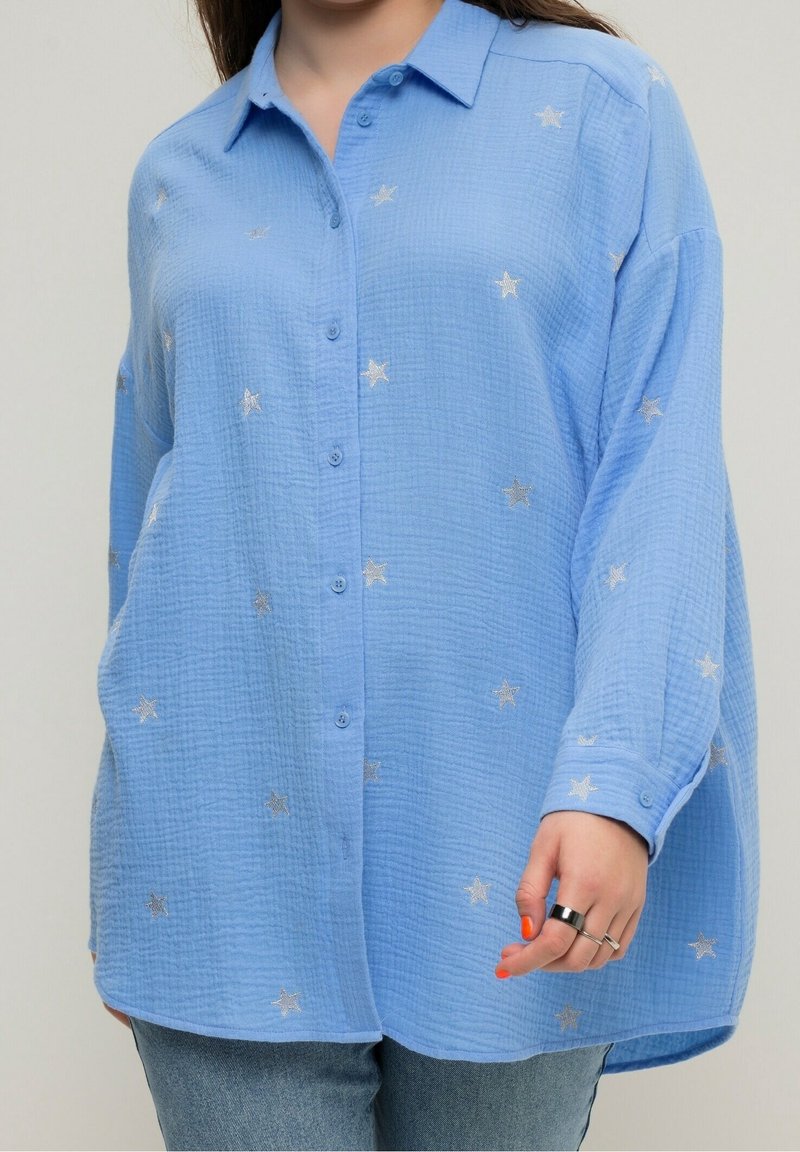 Chemise bleu clair boutonnée en tissu texturé, ornée de broderies d'étoiles argentées, coupe décontractée, manches longues avec poignets à boutons.
