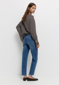 Braun-weiß gestreiftes Langarmshirt, blaue gerade Jeans und braune Ballerinas. Glatte Stofftextur mit lässigen Designelementen.