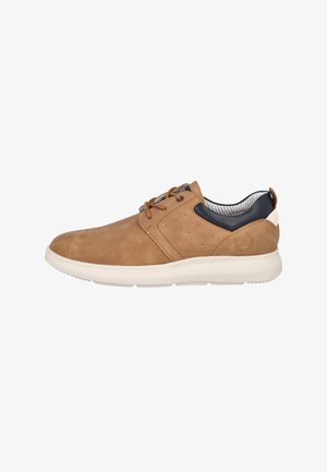 Zapatilla deportiva casual color beige con cordones, textura perforada, collarín acolchado negro en el talón, suela blanca y forro interior a rayas, vista de lado.