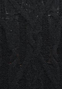 Schwarzer, gestrickter Pulloverstoff mit einem strukturierten Kabelmuster und unregelmäßigen Stichen, die leichte Variationen in der Dicke aufweisen.