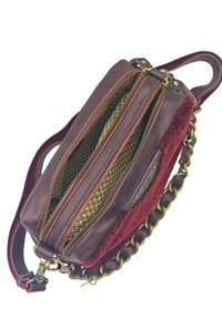 Petit sac à main en cuir marron et velours rouge avec des zippers dorés, une doublure intérieure à motifs, et une bandoulière en chaîne.