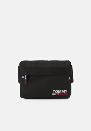 Sac banane noir Tommy Jeans avec rabat avant, petite étiquette drapeau et logo blanc et rouge sur la poche avant.