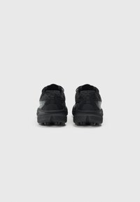Chaussures de sport noires avec un dessus en tissu texturé, un collier rembourré et une semelle extérieure en caoutchouc robuste. La vue arrière met en avant des accents réfléchissants.