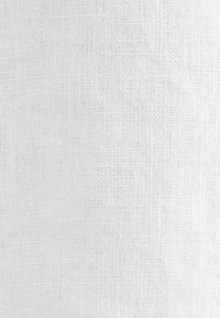 Gros plan d’un tissu blanc texturé avec un motif tissé en forme de grille montrant de fins fils et de légères variations de couleur et de tissage.