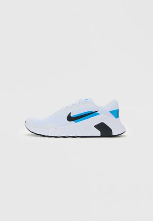 Weißer niedrig geschnittener Nike Laufschuh mit schwarzem Swoosh, blauen Akzenten und dicker Sohle, die mit "Nike Flex" gekennzeichnet ist, seitlich auf weißem Hintergrund gezeigt.