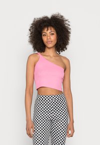Top cropped rosa de um ombro, feito de material ribbed, combinado com leggings pretas e brancas com padrão xadrez; textura suave, design ajustado.