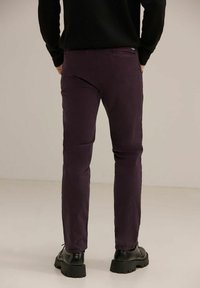 Tummanvioletit slim-fit-housut puuvillasekoitetta, joissa on takatasku ja minimalistinen muotoilu. Yhdistetty mustiin paksupohjaisiin bootseihin.