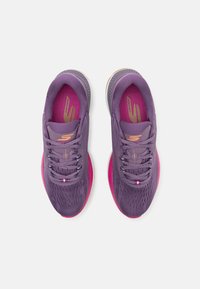 Paarse sportieve schoenen met een gestructureerde bovenkant, roze accenten op de tussenzool en subtiele branding. Voorzien van traditionele veters en een gevoerde kraag.