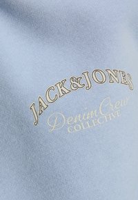 Sudadera de color azul claro hecha de tela suave, con el texto bordado "JACK & JONES" y "DenimCrew COLLECTIVE" en colores contrastantes.