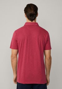 Kortärmad polo-shirt i mörkröd, tillverkad av lättviktig tyg med en mjuk textur, med en klassisk krage och en avslappnad passform.