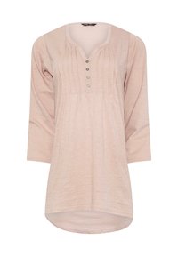 Tunique rose clair à manches longues avec un col en V, un devant plissé et un plastron à six boutons. Tissu doux avec un ourlet arrondi et une coupe décontractée.