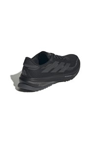 Scarpa da corsa nera Adidas con suola testurizzata, tre strisce laterali e logo "DREAMSTRIKE+" sulla suola intermedia, mostrata da un angolo posteriore leggermente inclinato.