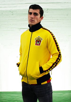 Felle gele trainingsjack met een rits en zwarte accenten, met een embleem en een geruite print langs de mouwen. Casual fit.