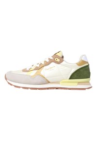 Zapatilla deportiva con parte superior de cuero blanco, puntera de ante gris, talón de ante verde y acentos amarillos; cuenta con un cierre de cordones en la parte frontal y suela de goma.