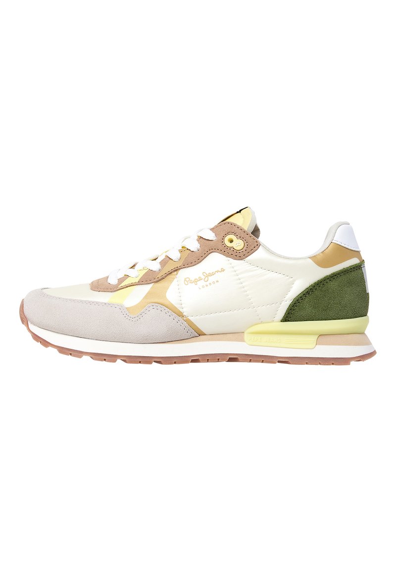 Zapatilla deportiva con parte superior de cuero blanco, puntera de ante gris, talón de ante verde y acentos amarillos; cuenta con un cierre de cordones en la parte frontal y suela de goma.