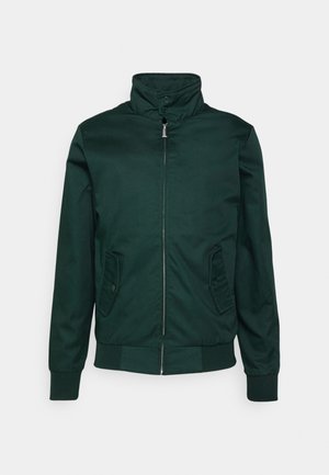 Veste bomber vert foncé avec un col montant, fermeture éclair à l'avant et poches latérales. Confectionnée en tissu lisse avec des poignets et un ourlet côtelés.