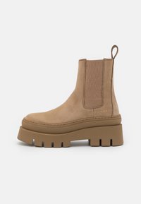Botine din suede bej, la nivelul gleznei, cu panouri elastice pe laterale, talpă groasă și buclă de prindere. Prezentă detalii cusute și o Textură netedă.