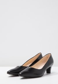Czarne skórzane szpilki z zaostrzonym noskiem, niskim słupkiem i gładką fakturą. Wnętrze wyłożone cielistą podszewką, w stylu minimalistycznym.