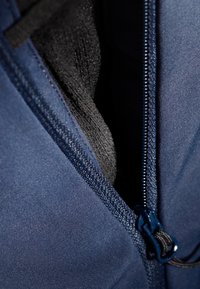 Granatowa kurtka z zamkiem częściowo otwartym, odsłaniającą czarną polarową podszewkę. Cechy obejmują gładką teksturę tkaniny oraz solidne metalowe okucia.