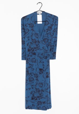 Vestido azul de manga larga con estampado floral negro y escote en V colgado en una percha negra sobre un fondo blanco.