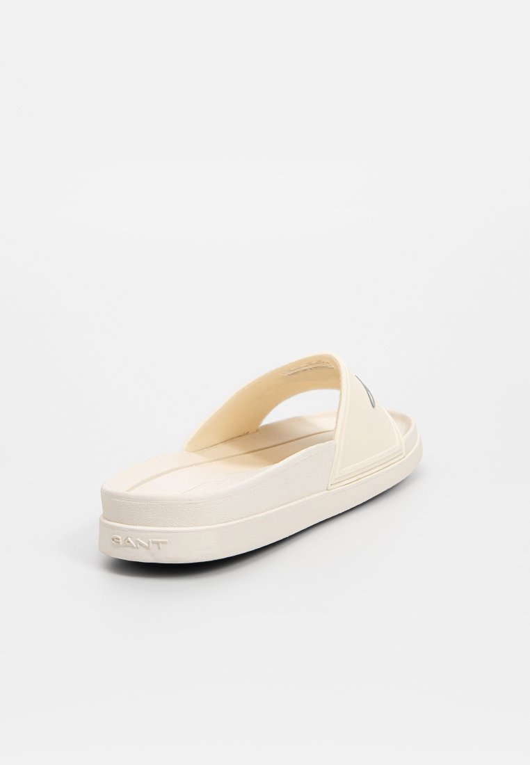 Beige Flip-Flop-Sandale mit einem breiten Riemen und strukturiertem Fußbett. Die Sohle ist leicht erhöht und zeichnet sich durch ein minimalistisches Design und Logo-Details aus.