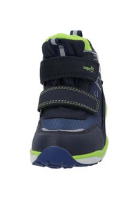 Scarpa sportiva blu navy con accenti verdi, caratterizzata da materiali in rete e sintetici, cinture in velcro e suola in gomma con dettagli testurizzati.