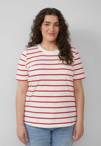 Rood-wit gestreepte T-shirt van zacht katoen, met een ronde halslijn en korte mouwen, gedragen met blauwe denim jeans.