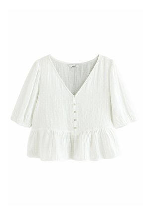 Camicia bianca semitrasparente con tessuto strutturato, scollo a V, cinque piccoli bottoni, maniche tre quarti e orlo arricciato.
