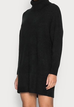 Sort langærmet rulneck-strikkjole båret af en person, ribstrikkede manchetter og kant, midt på låret længde, ensfarvet strikket tekstur.