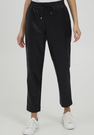 Zwarte joggingsbroek van soepel, rekbaar materiaal met een elastische tailleband en verstelbaar trekkoord, met taps toelopende boorden en strakke lijnen.