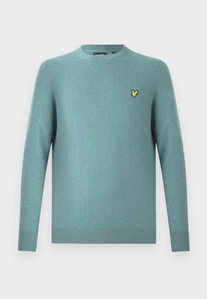 Pull col rond en tissu bleu sarcelle doux, avec manches longues et ourlet à côtes. Logo jaune brodé en accent sur la poitrine.