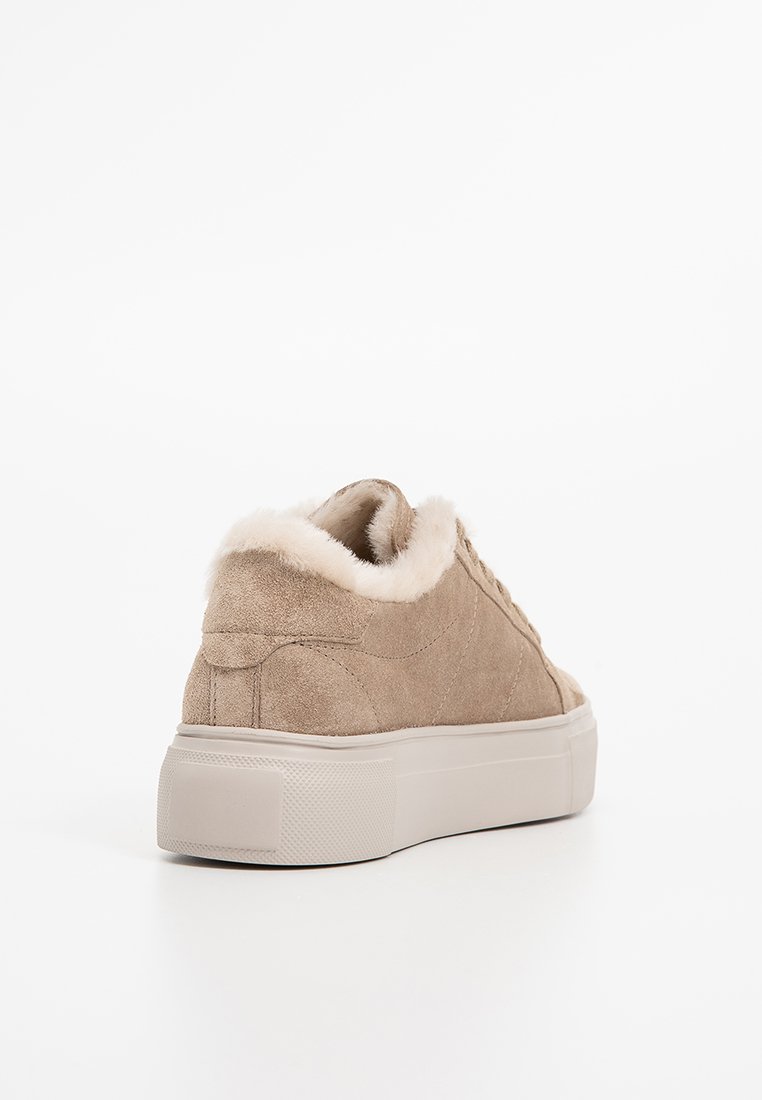 Beige Wildledersneaker mit einem cremefarbenen Kunstfellfutter, gepolsterter Kante und einer dicken, weißen Gummisohle. Minimalistisches Design, niedrig geschnitten.