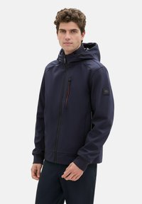 Marineblaue Jacke mit Reißverschluss und Kapuze, ausgestattet mit elastischen Bündchen, einer Brusttasche mit einem kontrastierenden Reißverschluss und einer glatten, strukturierten Stoffoberfläche.