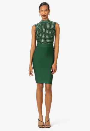 Strak groene jurk met een gestructureerde, met studs versierde lijf en een soepele pencil skirt. Hoge kraag en mouwloos ontwerp met een slanke silhouet.