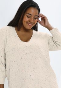 Crème V-hals trui met een gestructureerde brei en meerkleurige spikkels, met losse mouwen en een ontspannen pasvorm.