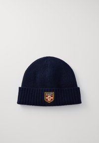 Navy blue knitted beanie made of ribbed fabric, featuring a folded cuff and a shield-shaped patch with "GANT" and "1949" in contrasting colors.