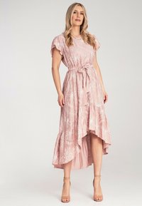 Sukienka maxi w jasnoróżowym kolorze z białymi kwiecistymi wzorami, krótkimi falbaniastymi rękawami, wiązanym w pasie oraz asymetrycznym dołem. Gładka tekstura, lekki materiał.