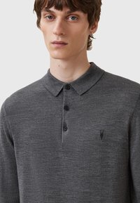 Langærmet polo i mørkegrå lavet af blødt, tekstureret stof. Har en klassisk krave, tre-knaps åbning og et diskret logo på brystet.