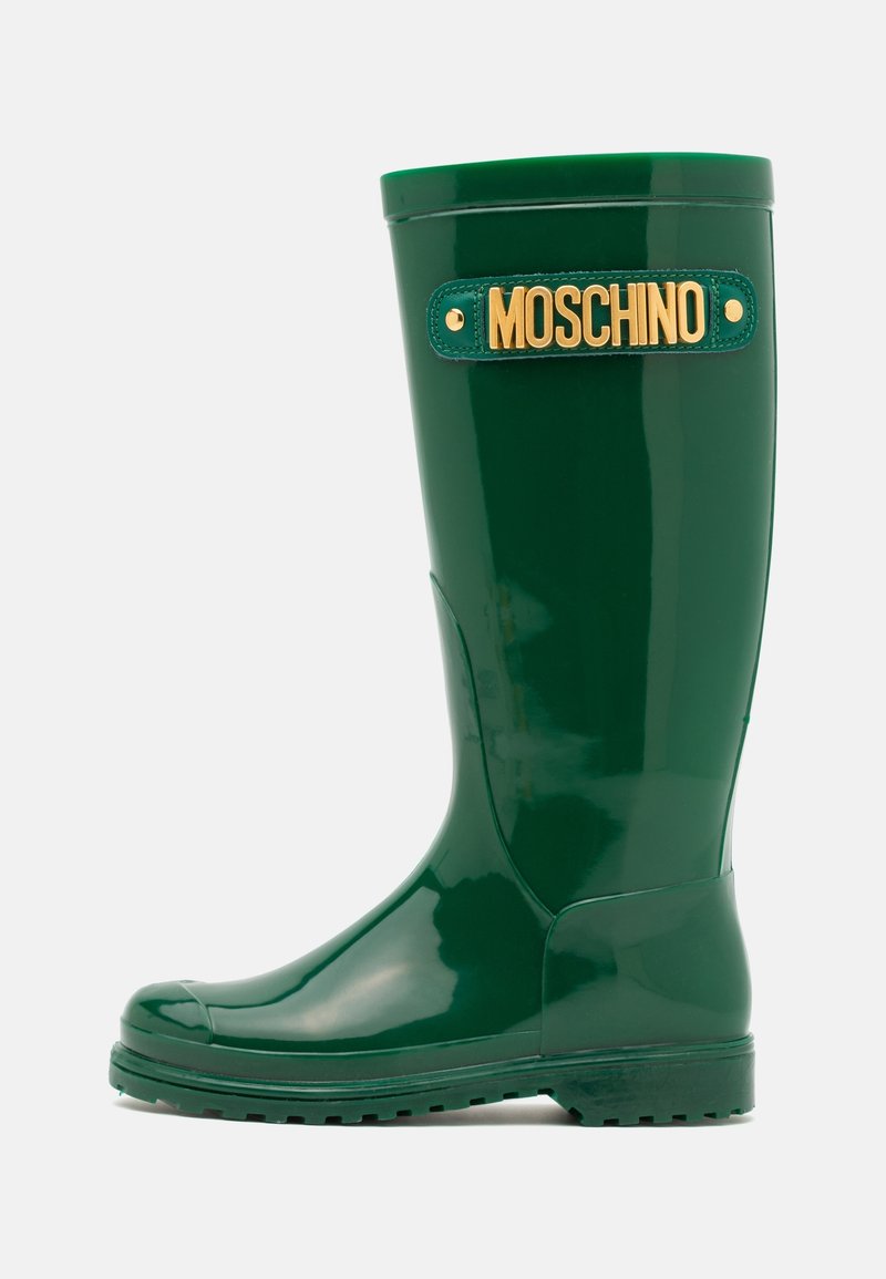 Botte de pluie en caoutchouc verte avec une finition brillante, comprenant un accent logo doré et une semelle texturée pour l'adhérence. Couleur unie, design haut.