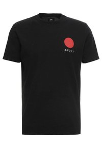 Svart bomull t-skjorte med en liten rød sirkel og japansk tekst på venstre brystområde. Klassisk rund hals og korte ermer.