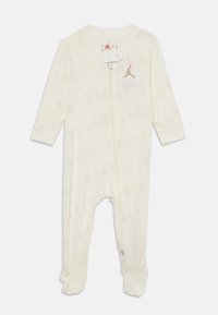 White jumpsuit with long sleeves, featuring a subtle "JORDAN" pattern, zip closure, and a small gold logo on the chest. Soft fabric.