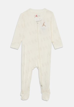 Witte jumpsuit met lange mouwen, voorzien van een subtiele "JORDAN"-print, ritsluiting en een klein gouden logo op de borst. Zachte stof.