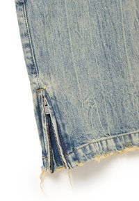 Falda de mezclilla azul claro con dobladillo deshilachado y detalle de cremallera lateral. La tela presenta un lavado desvanecido con sutiles texturas y costuras.
