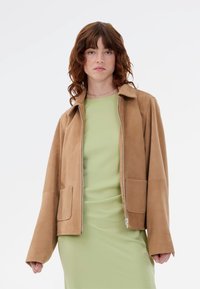 Καφέ σουέτ μπουφάν με δομημένο γιακά, μακριά μανίκια και δύο μπροστινές τσέπες. Ο σχεδιασμός περιλαμβάνει φερμουάρ μπροστά και λεία υφή.